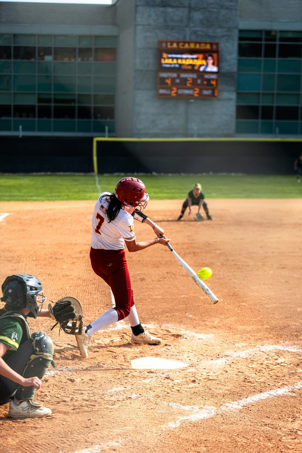 Joueuse de softball frappant la balle, le receveur accroupi derrière elle